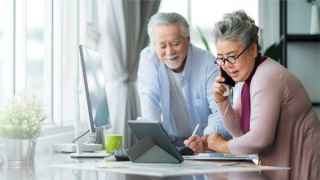 Senior couple working together on the computer at home