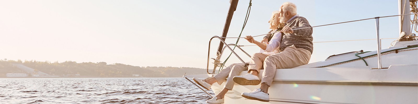 Happy senior couple sitting on sailboat enjoying the sea view